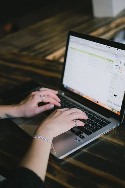 Person analyzes stock data with a smartphone and laptop, indoors.